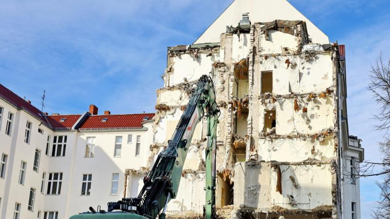 Excavadora al lado de un edificio medio derruido